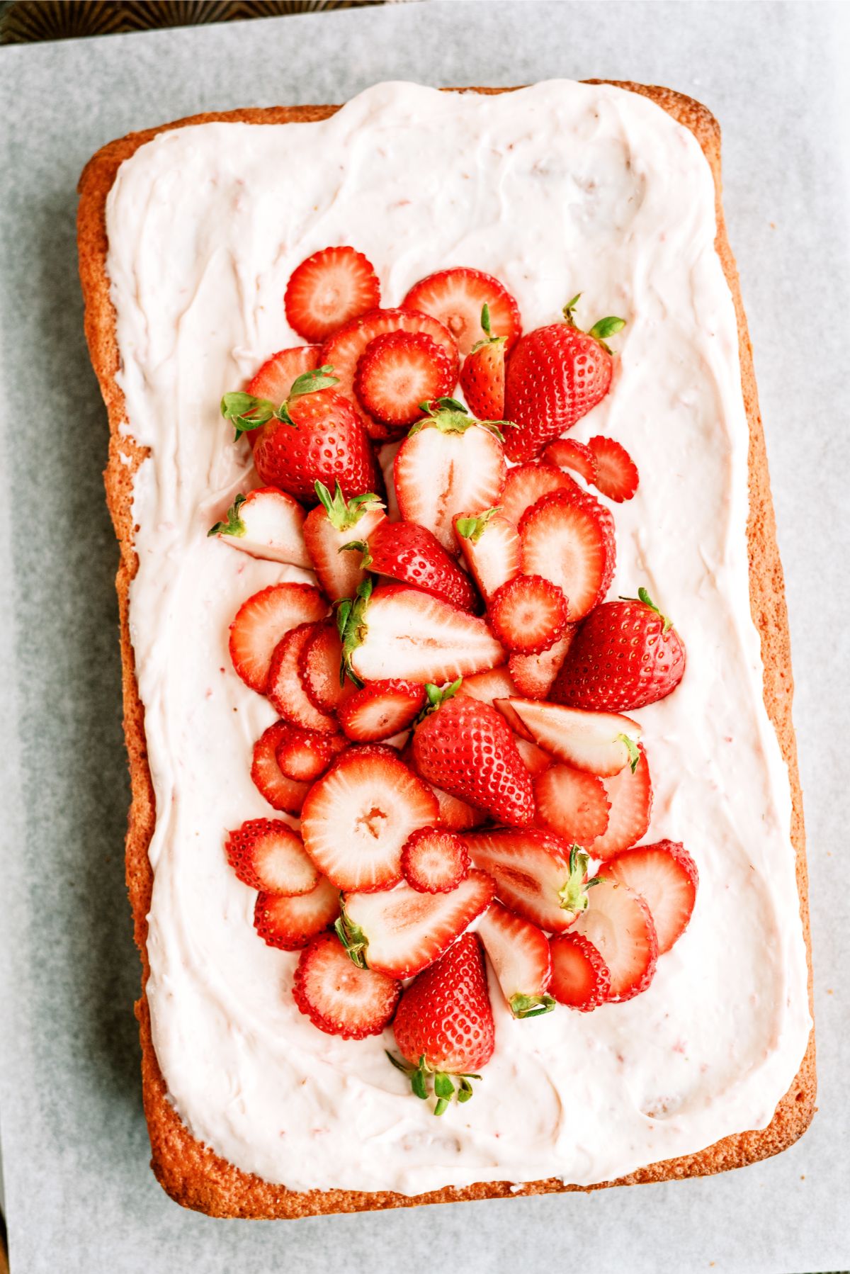Frosted Strawberry Sheet Cake on parchment paper