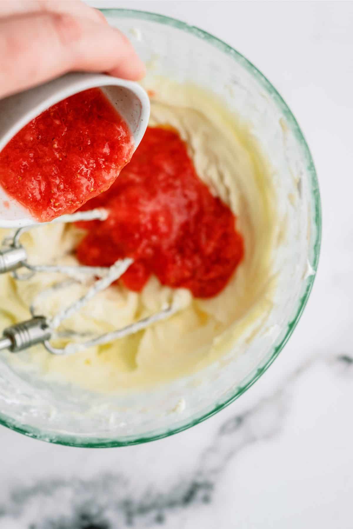 Adding strawberry preserves to mixing bowl of cake batter.