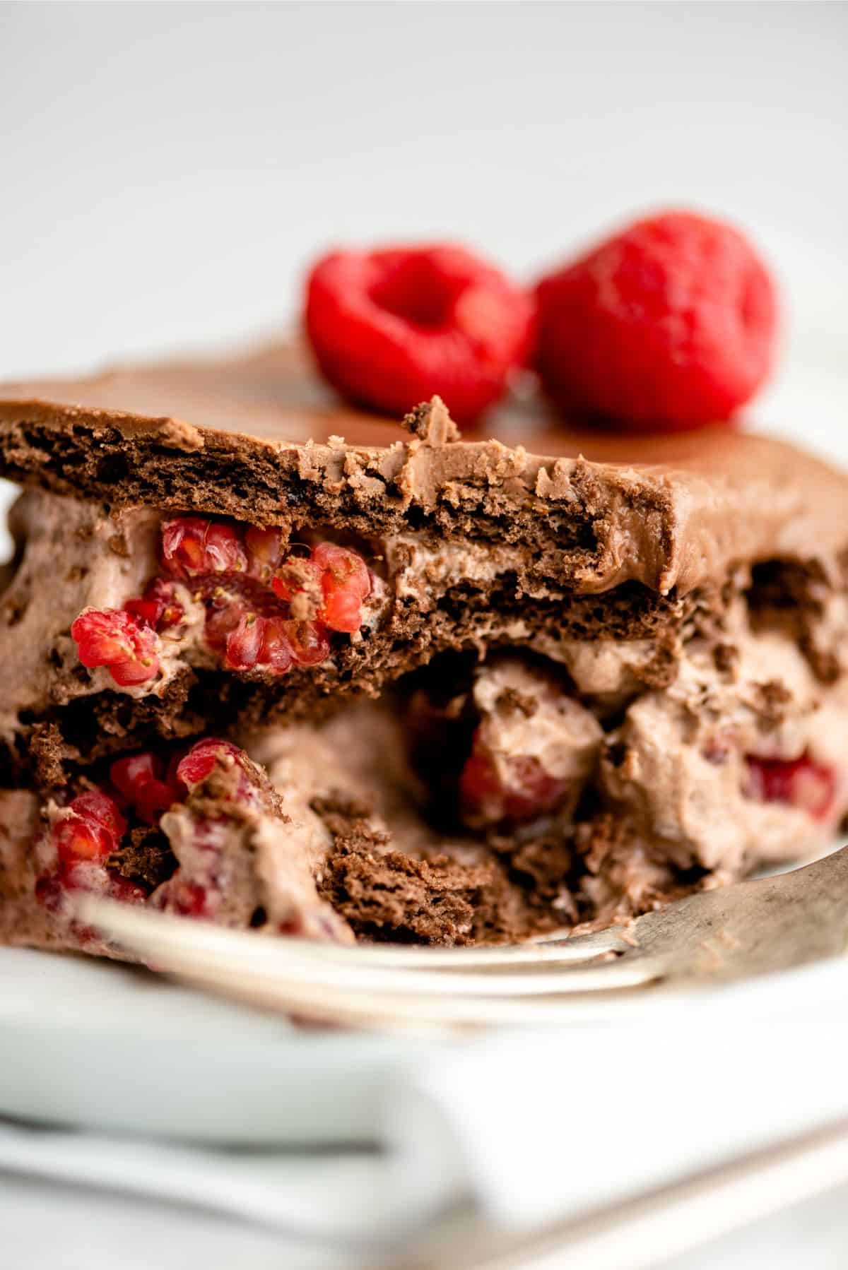 Close up of a slice of Chocolate Raspberry Eclair Cake on a plate with a fork.