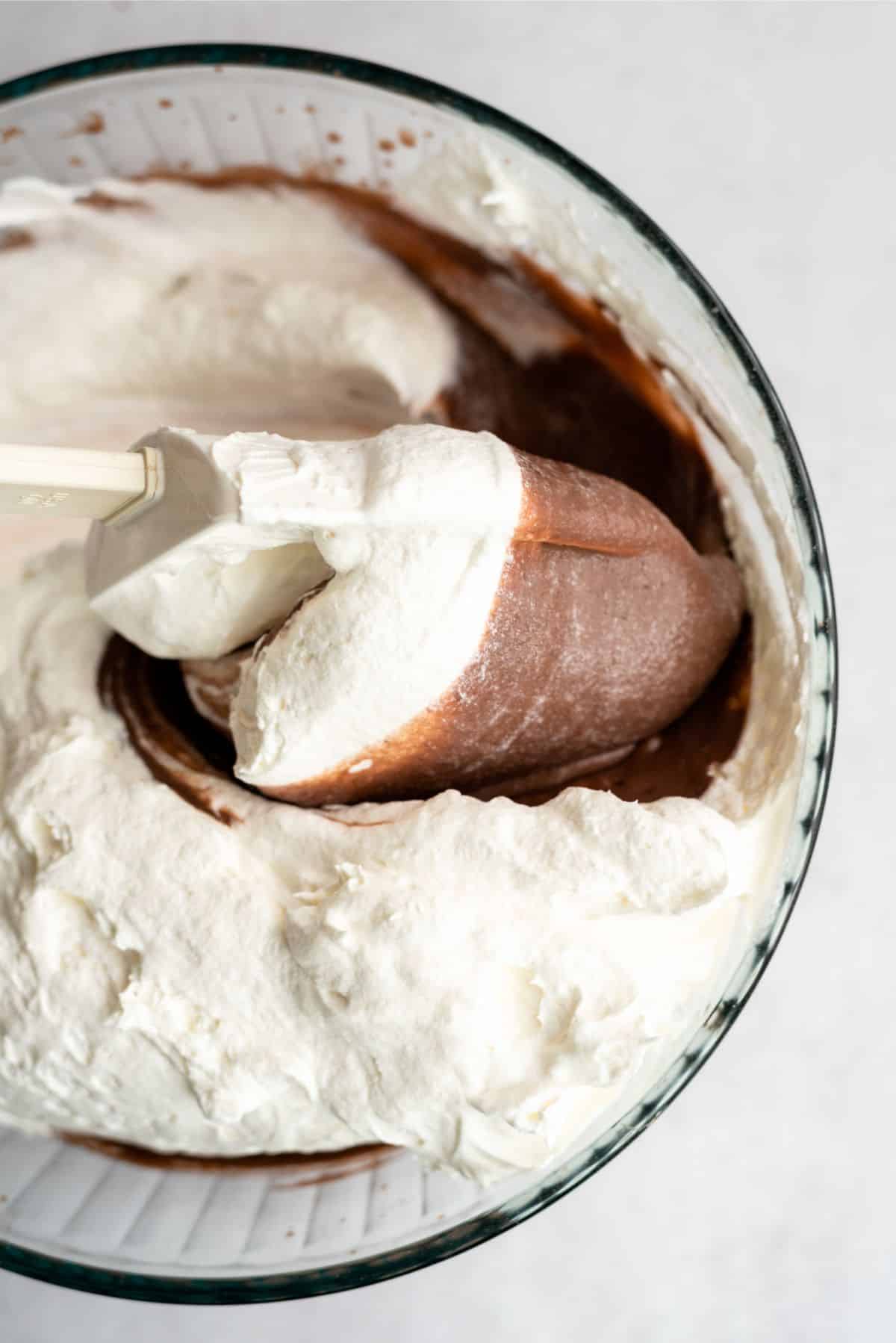 Mixing cool whip into chocolate pudding in a mixing bowl