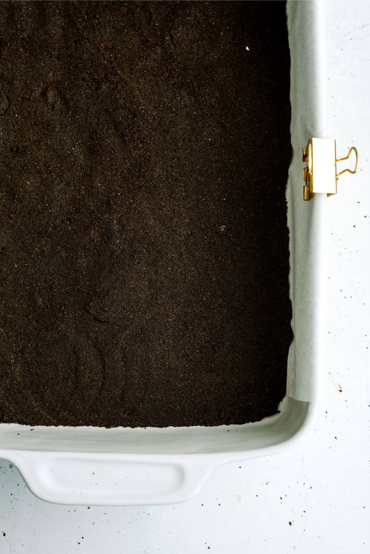 Oreo crust pressed into a baking dish lined with parchment paper.