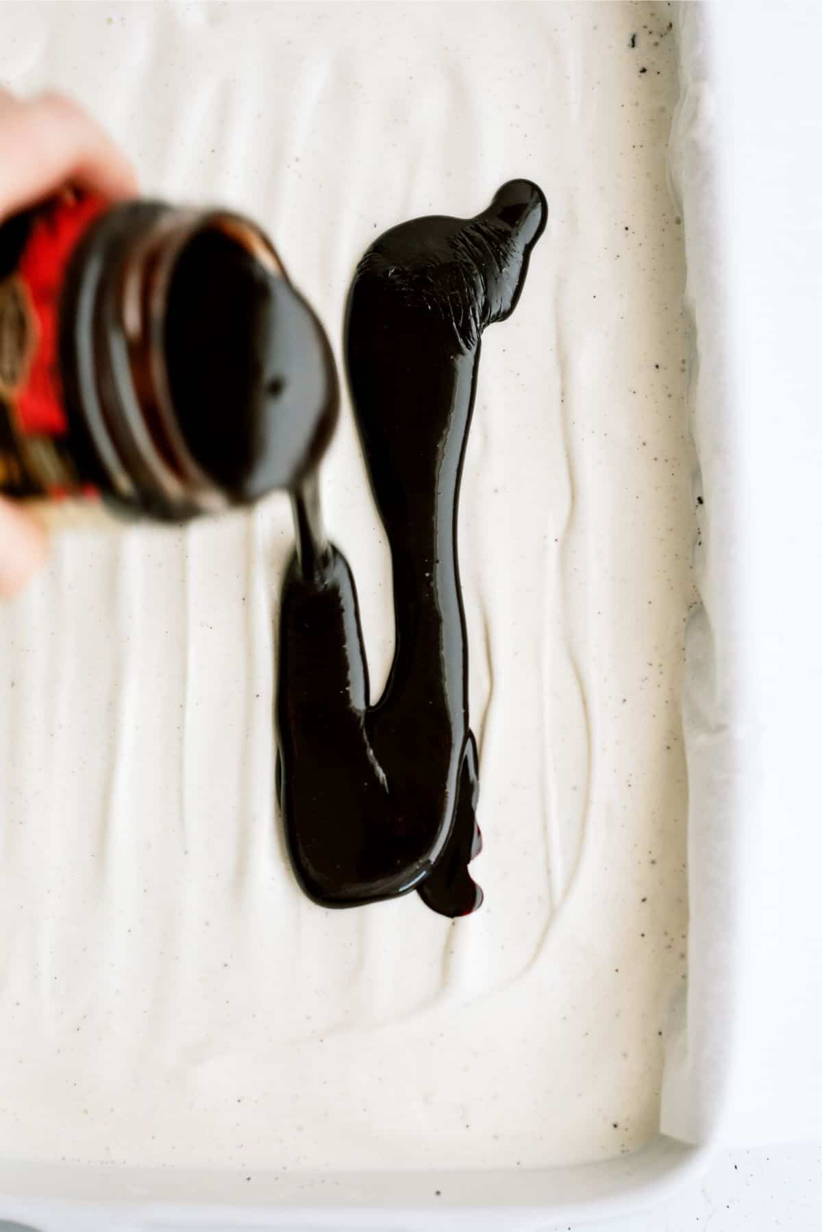 Chocolate sauce poured on top of ice cream layer in baking dish.