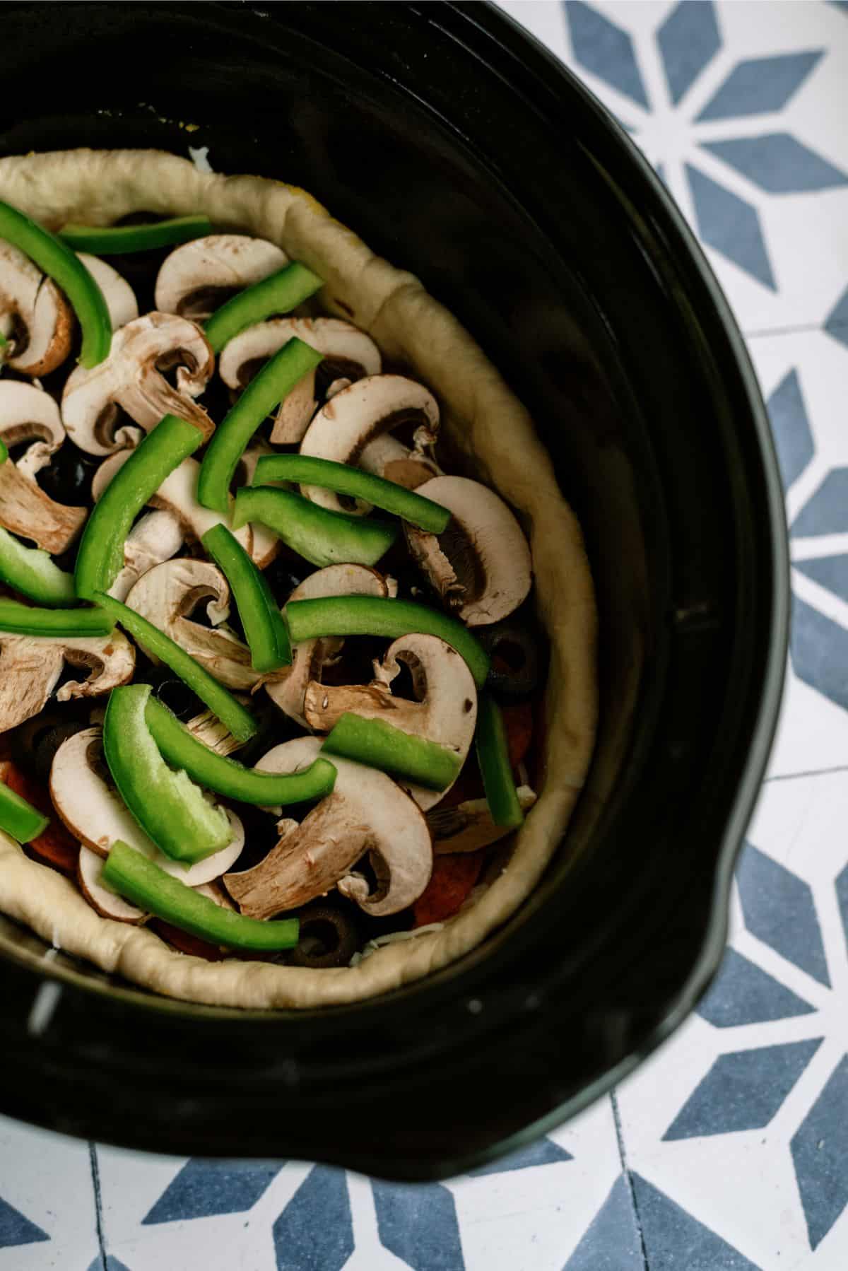 Sliced veggies layered on top of marinara sauce 