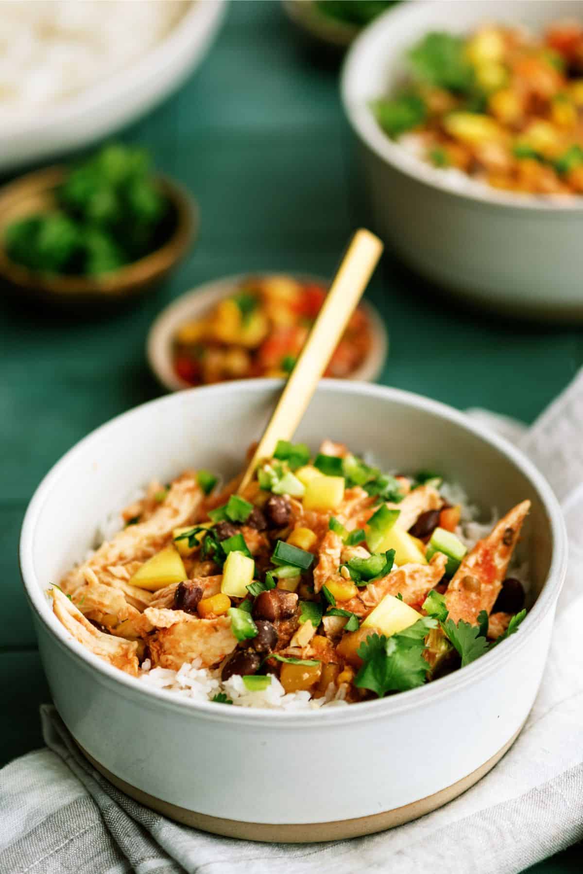 Slow Cooker Mango Chicken in a bowl on top of rice with a fork