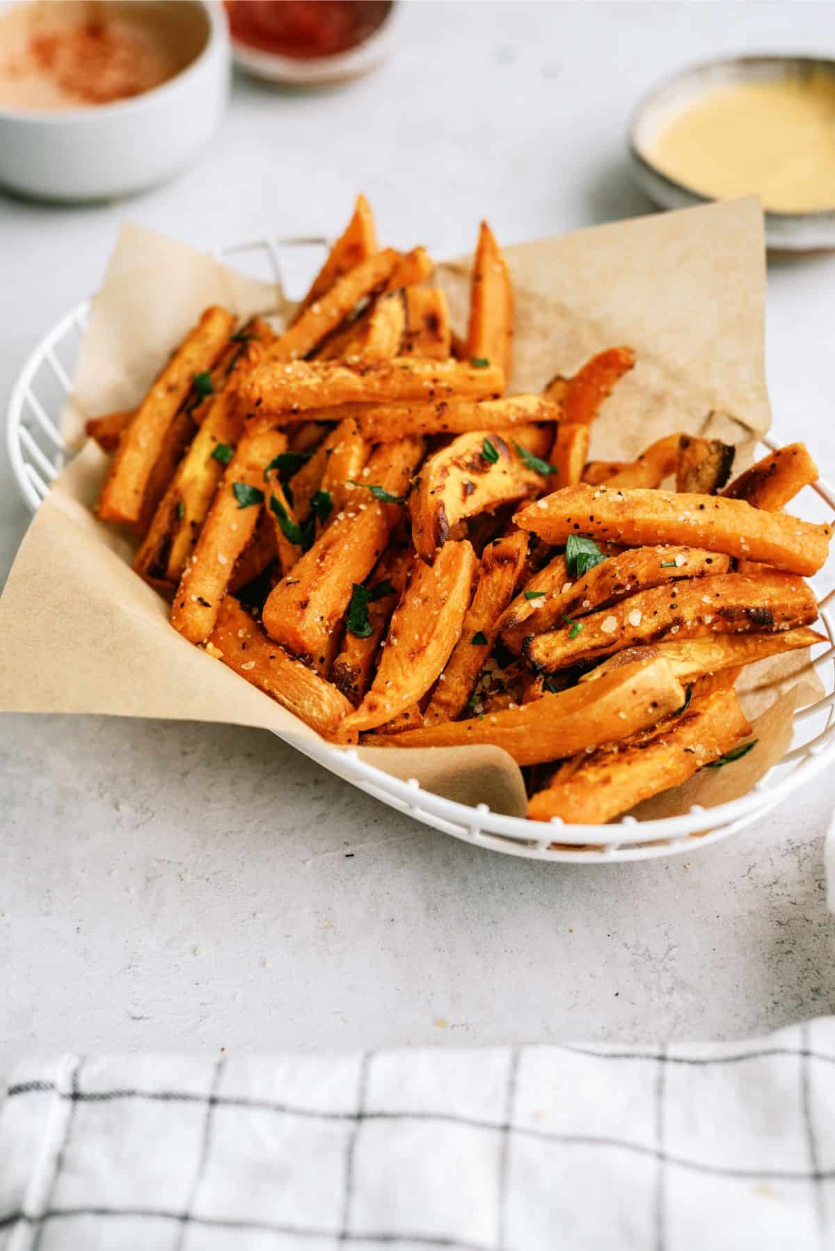 A basket of Baked Sweet Potato Fries with dipping sauce in the background