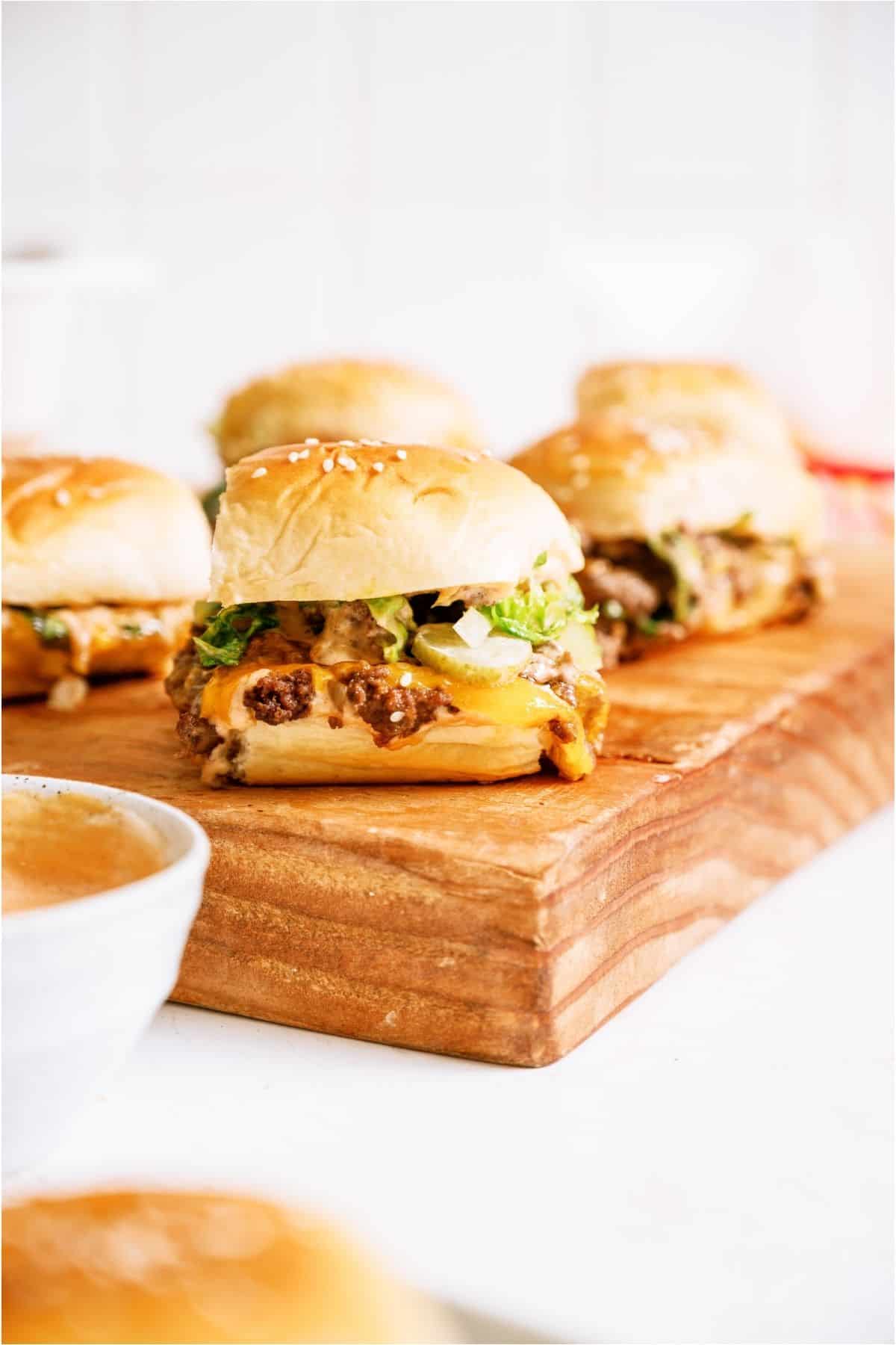 Big Mac Sliders on a cutting board with a small side of sauce.