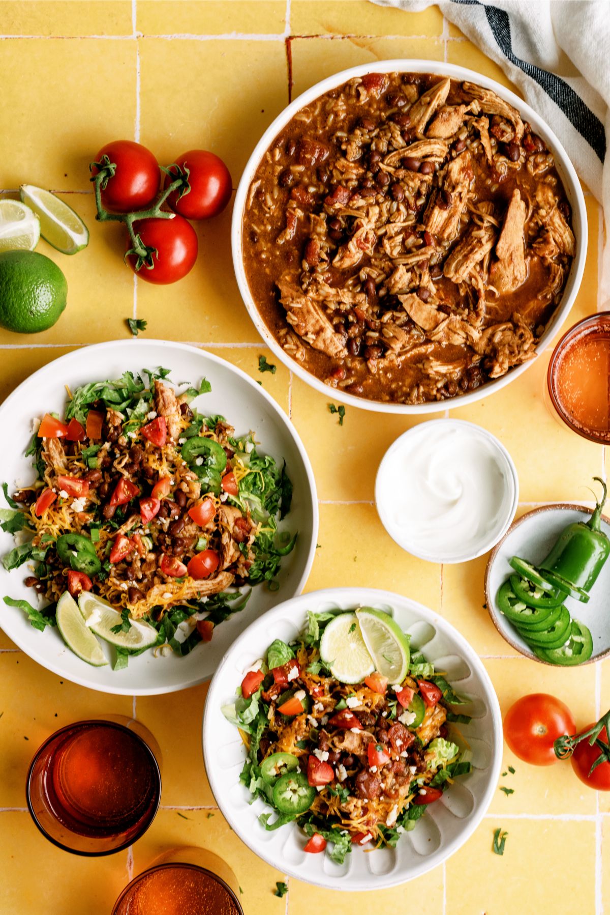 Top view of 2 Instant Pot Chicken Burrito Bowls with toppings and a bowl of Instant Pot Chicken Burrito Bowl shredded chicken