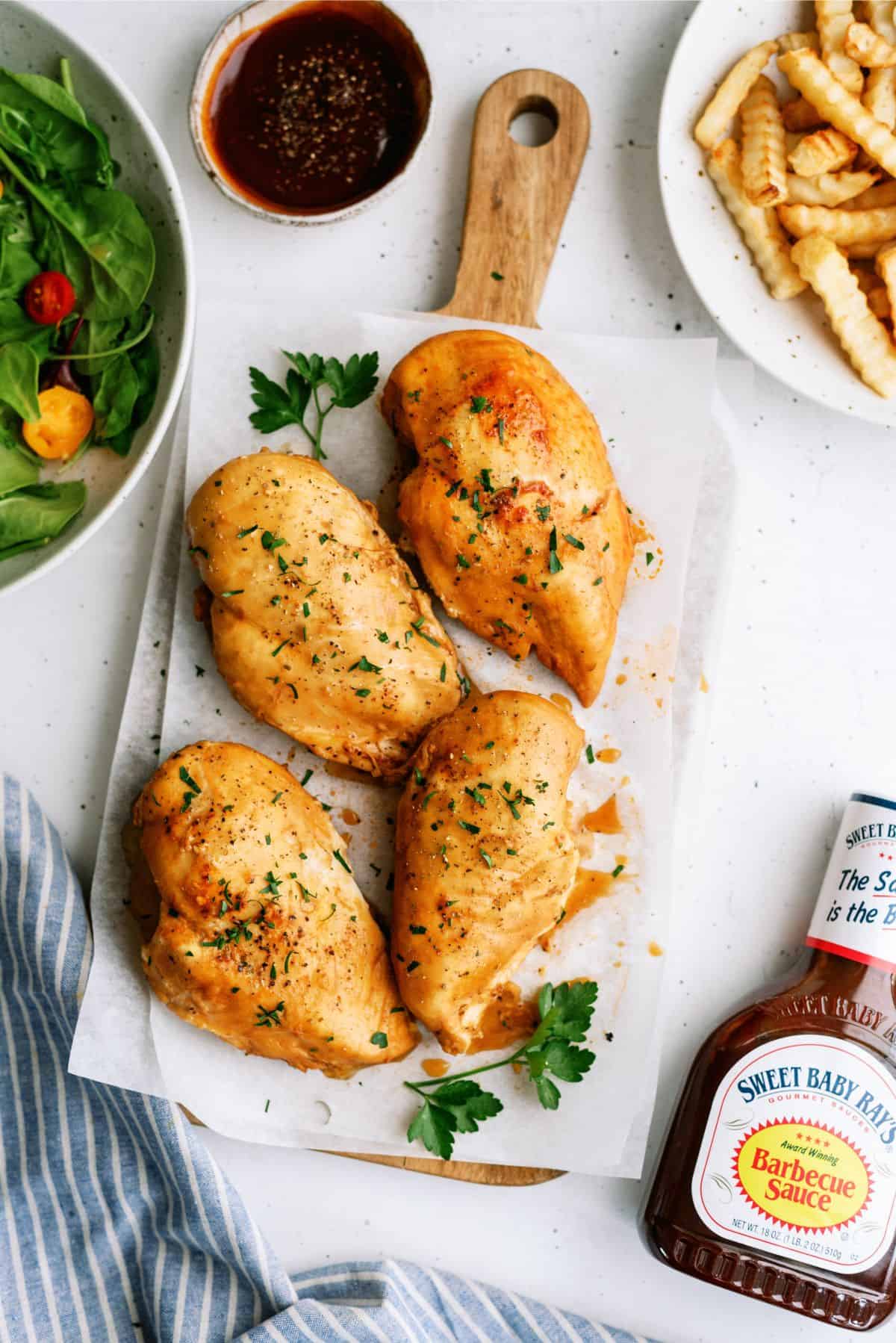 Instant Pot Sweet Baby Ray's Chicken on a cutting board with fries and salad on the side