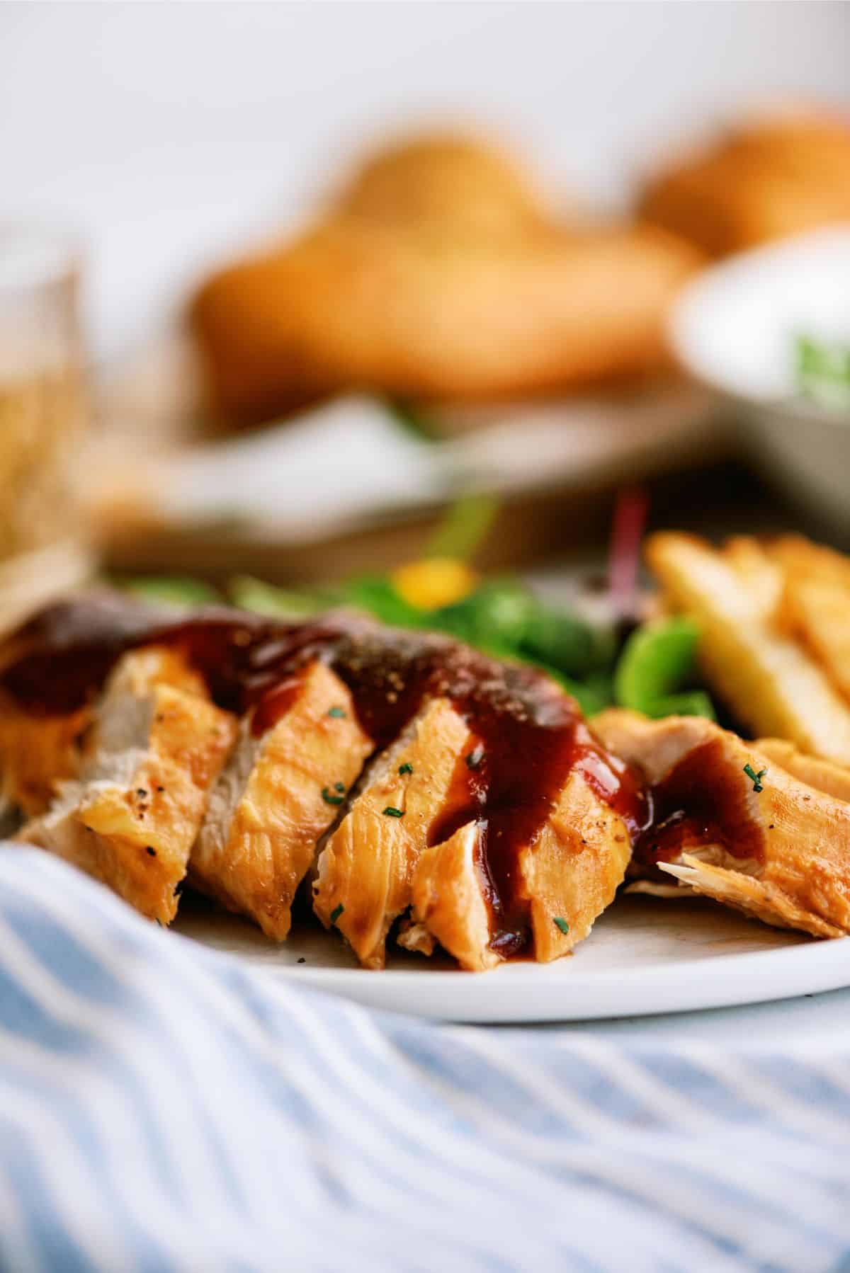 Instant Pot Sweet Baby Ray's Chicken sliced on a plate topped with BBQ sauce