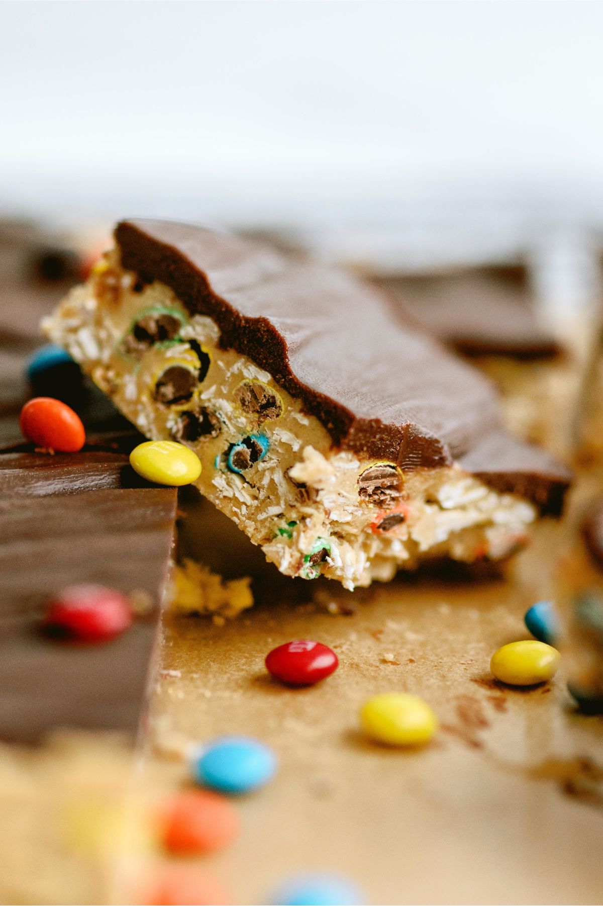 A Monster Cookie No Bake Bar slanted on top of other bars surrounded by M&M's