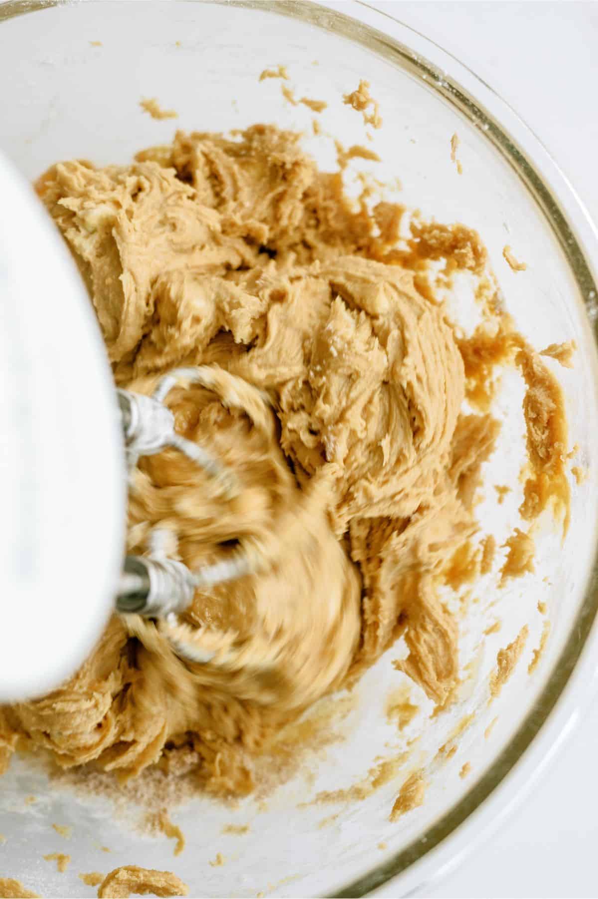 Monster Cookie No Bake Bars dough in a glass bowl with a hand mixer.