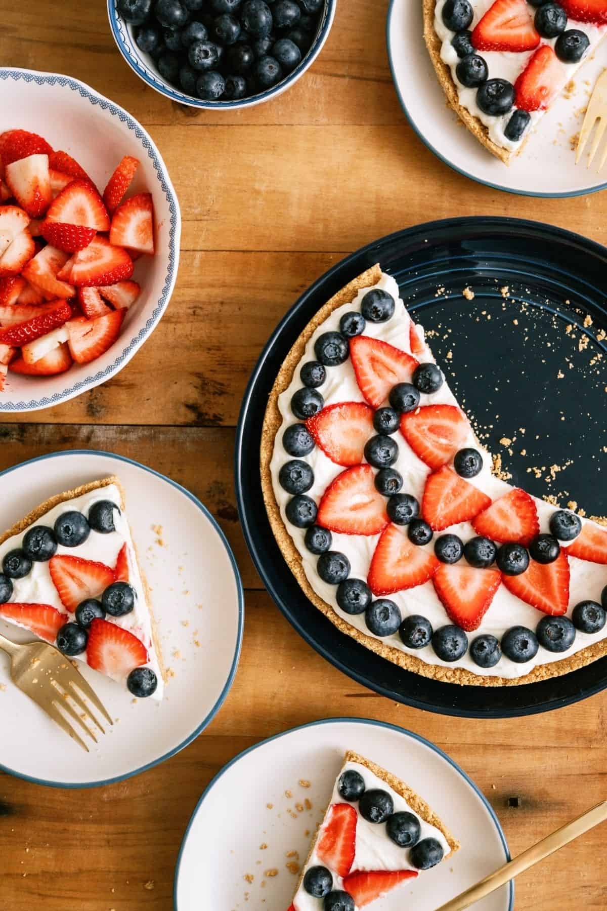 Patriotic Fruit Pizza sliced, with two slices on plates.