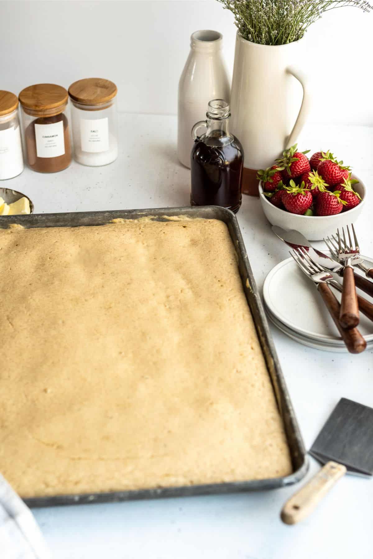 Sheet Pan Pancakes in the sheet pan with syrup and berries on the side