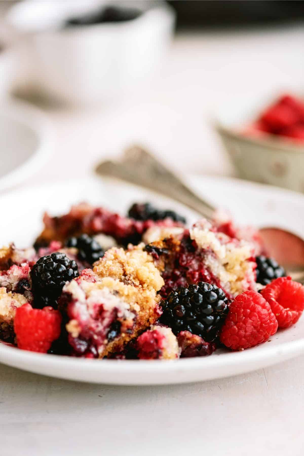A serving of Slow Cooker Berry Cobbler on a plate with a spoon.