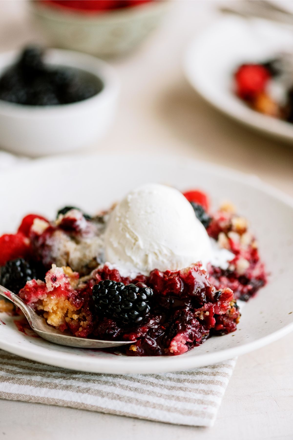 A serving of Slow Cooker Berry Cobbler on a plate topped with ice cream