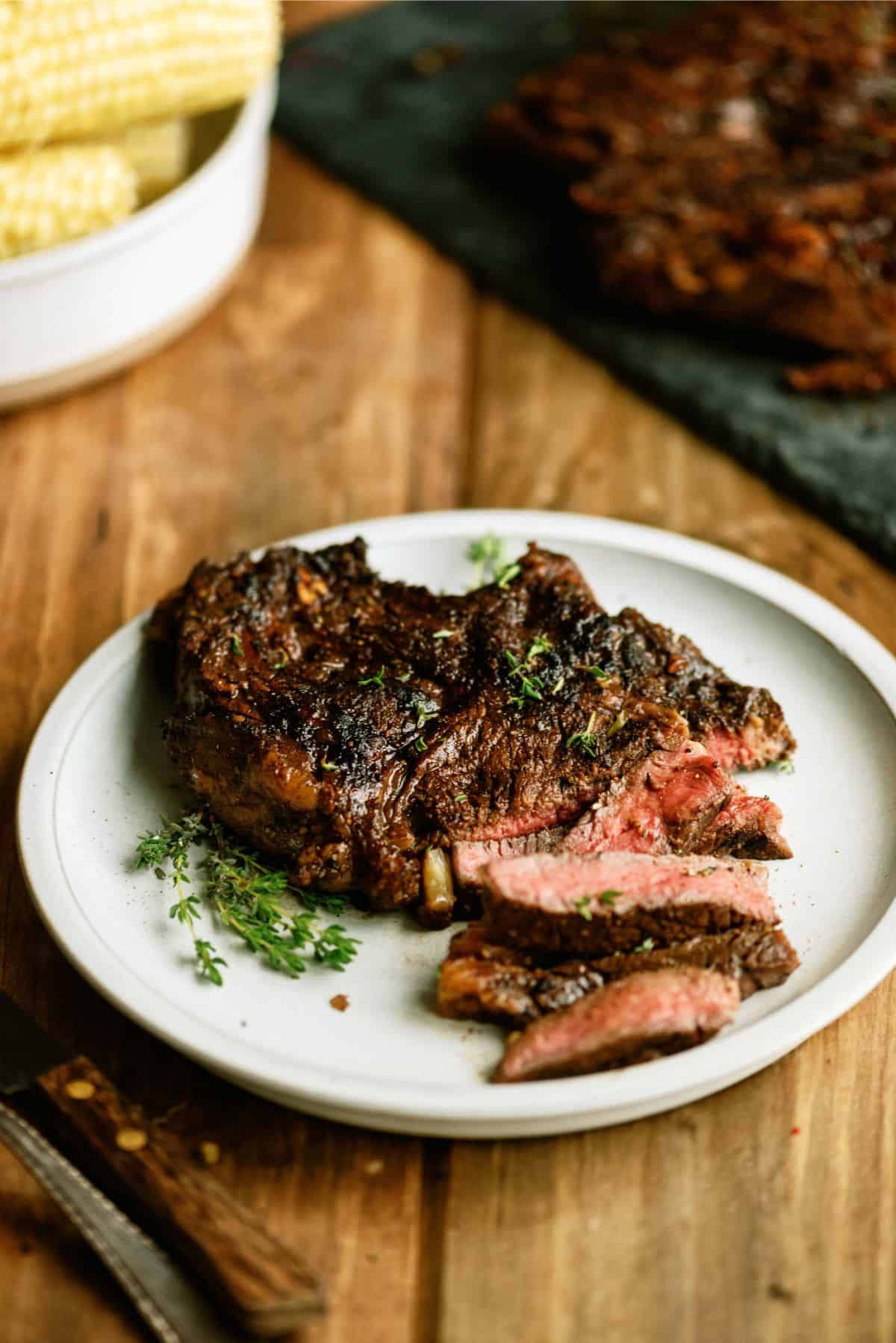 Tangy Marinated Steak on a plate with some pieces sliced