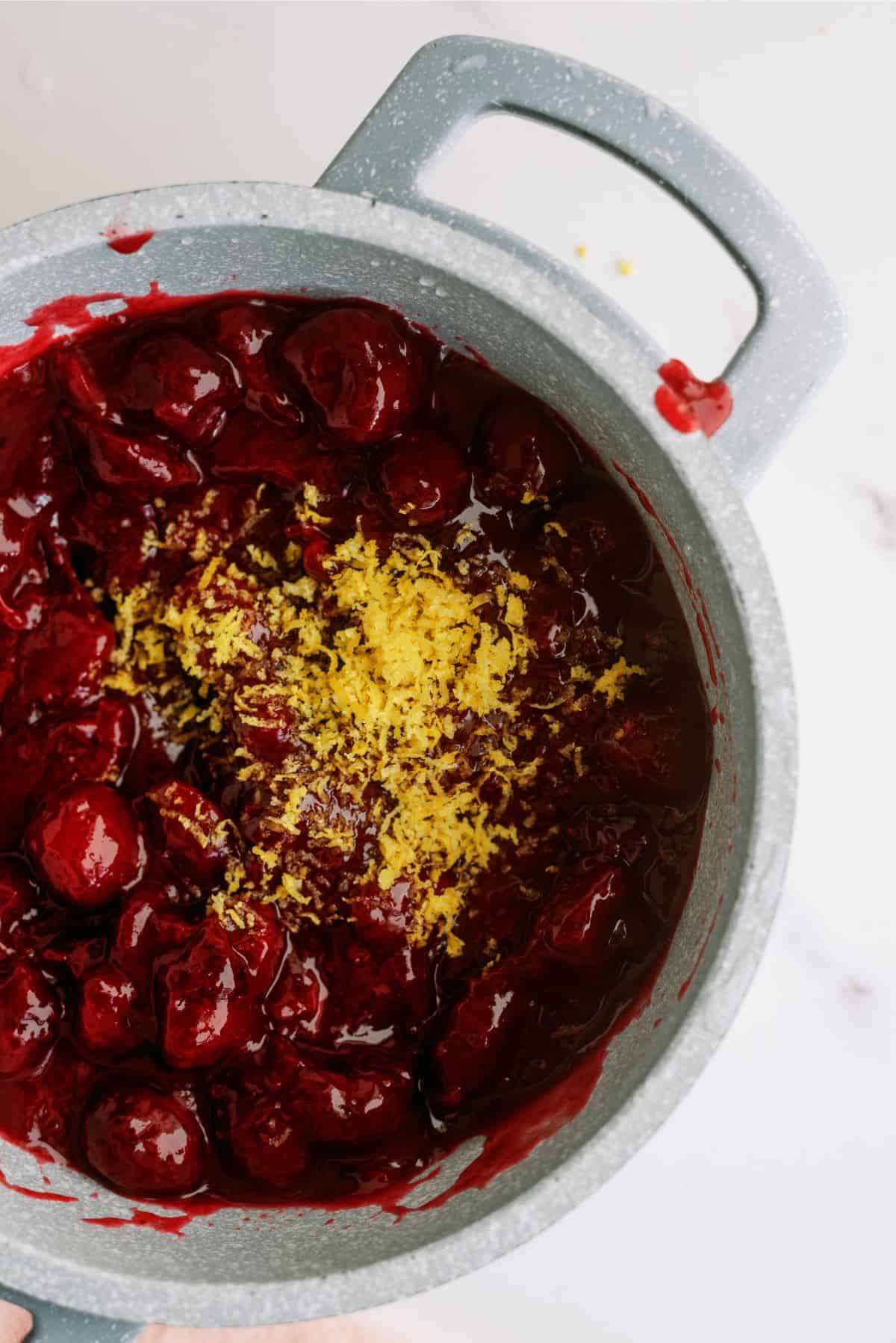 Cherry Cobbler mixture in saucepan with lemon zest on top.