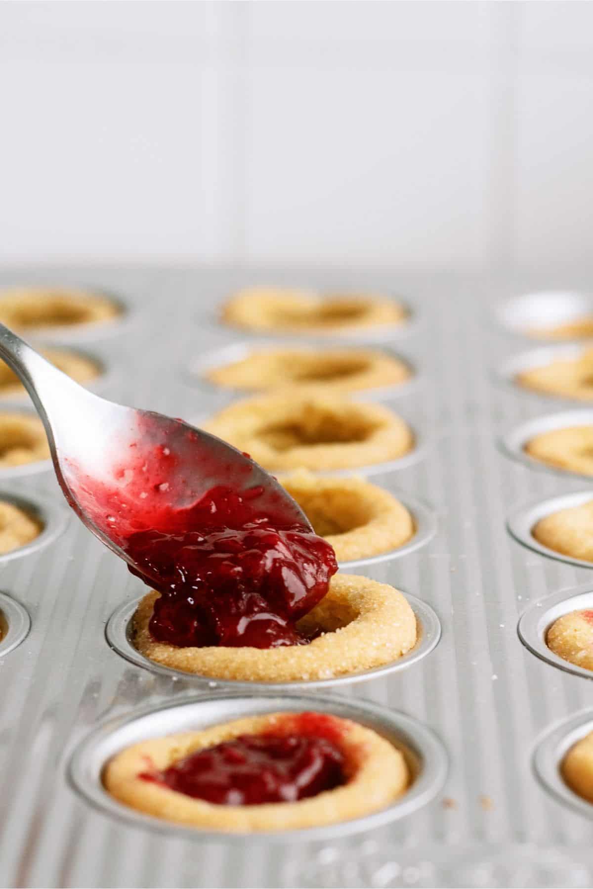 Spooning cherry cobbler mixture into each cookie cup in muffin tin.