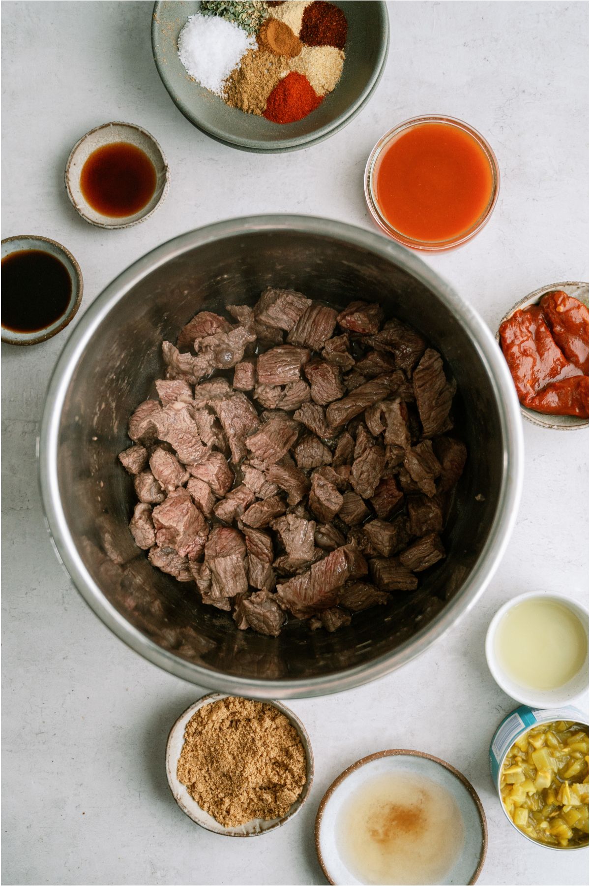 Browned beef inside an Instant Pot with the remaining Copycat Chipotle Barbacoa surrounding the pot.
