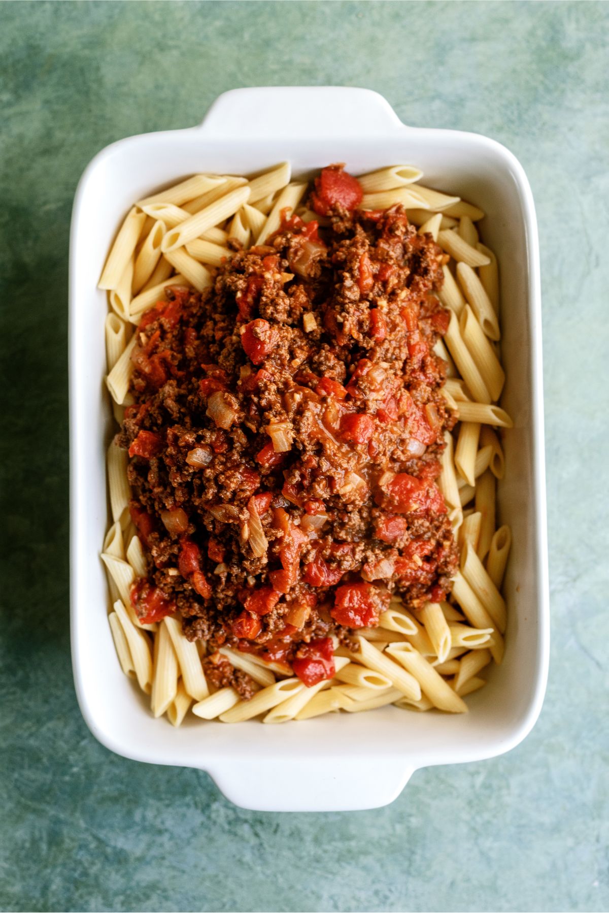 Meat sauce on top of noodles in casserole dish