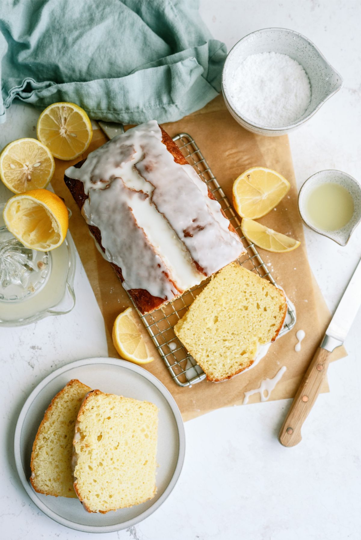 Lemon Yogurt Bread on a cutting board with lemon juice and powdered sugar in the back ground