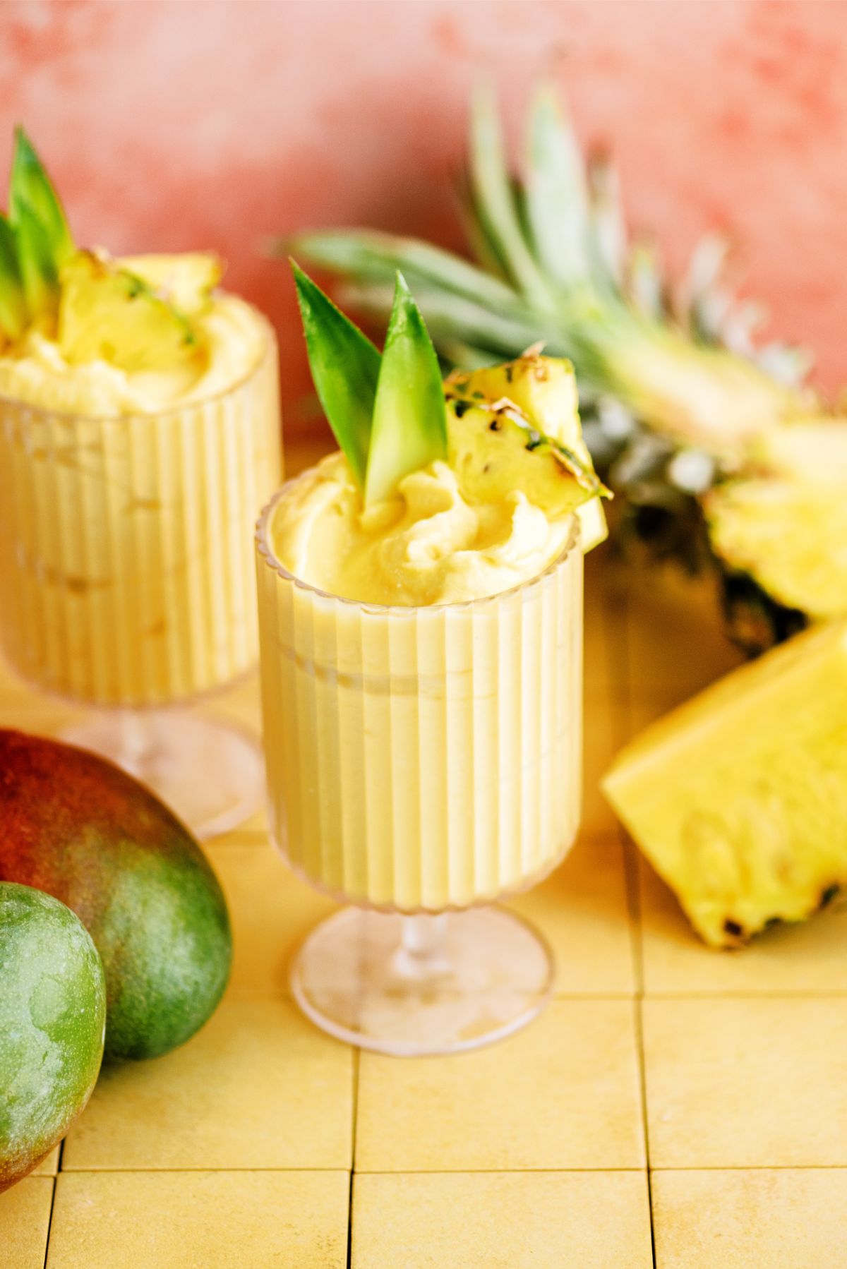 Mango and Pineapple Dole Whip in a glass surrounded by Pineapple and Mangoes