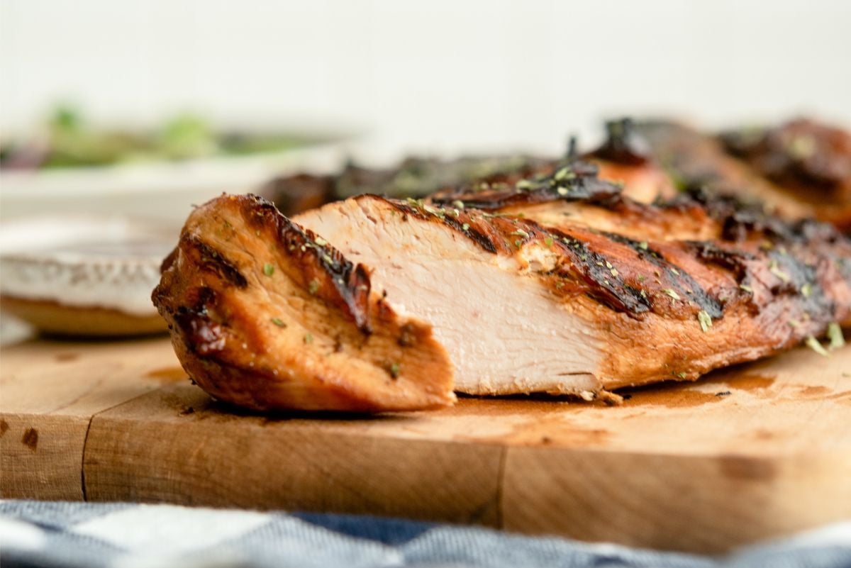 Marinated Root Beer Grilled Chicken on a cutting board with one slice