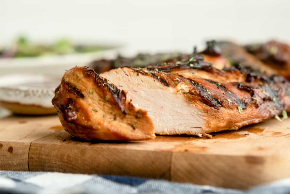 Marinated Root Beer Grilled Chicken on a cutting board with one slice