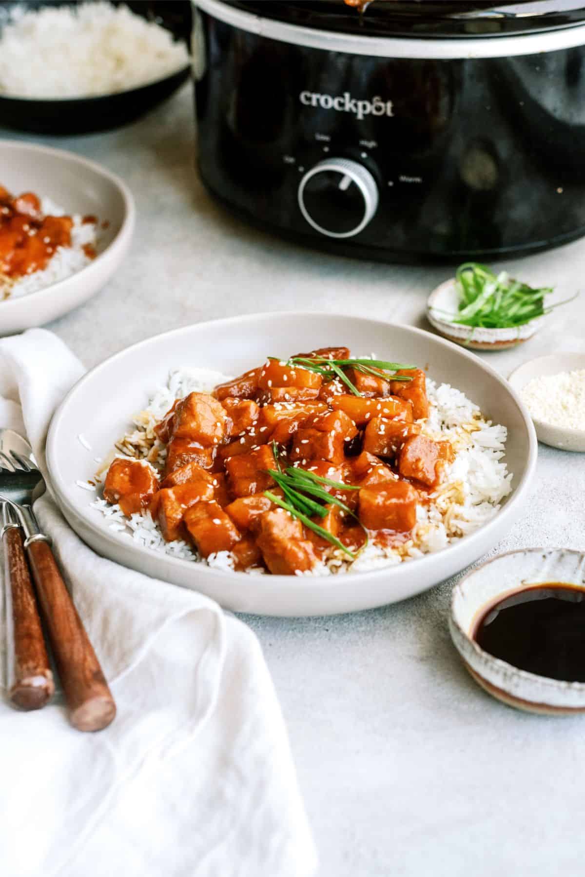 Slow Cooker Sweet and Tangy Pork served over rice with the slow cooker in the background