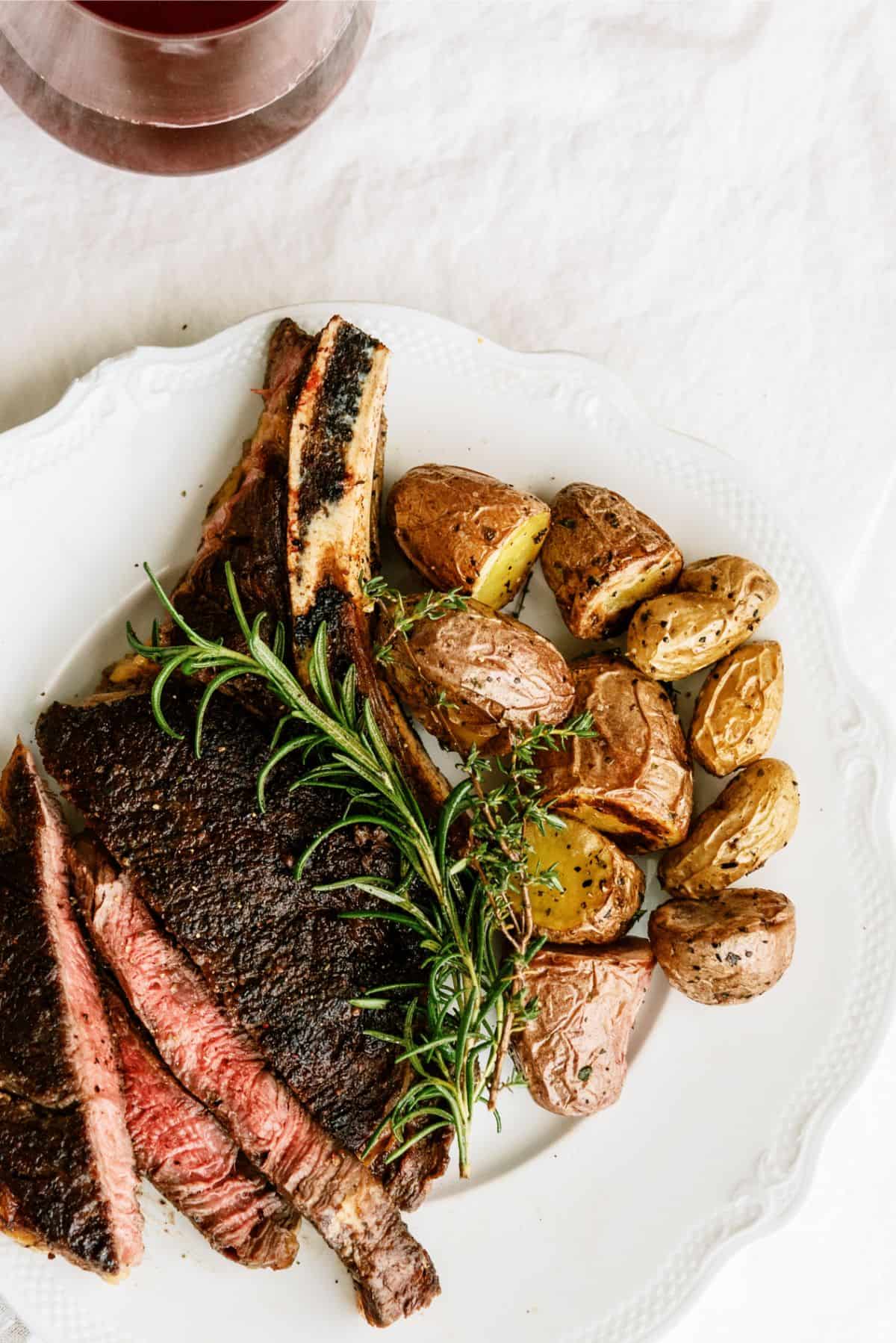 Top view of New York bone in steak grilled on a plate with potatoes