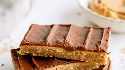 3 chocolate peanut butter bars stacked on top of each other on a white background.