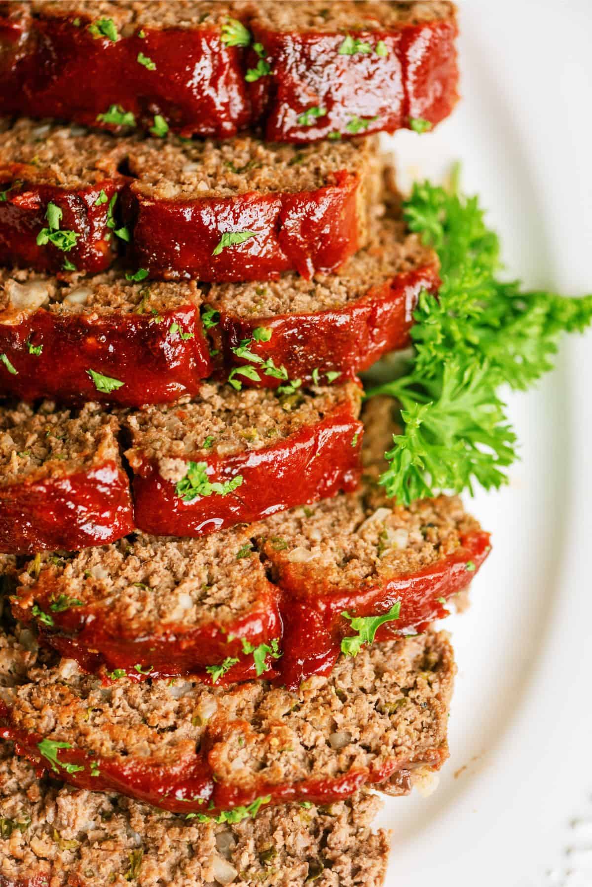 Delicious meatloaf slices topped with ketchup and fresh parsley on a white plate.