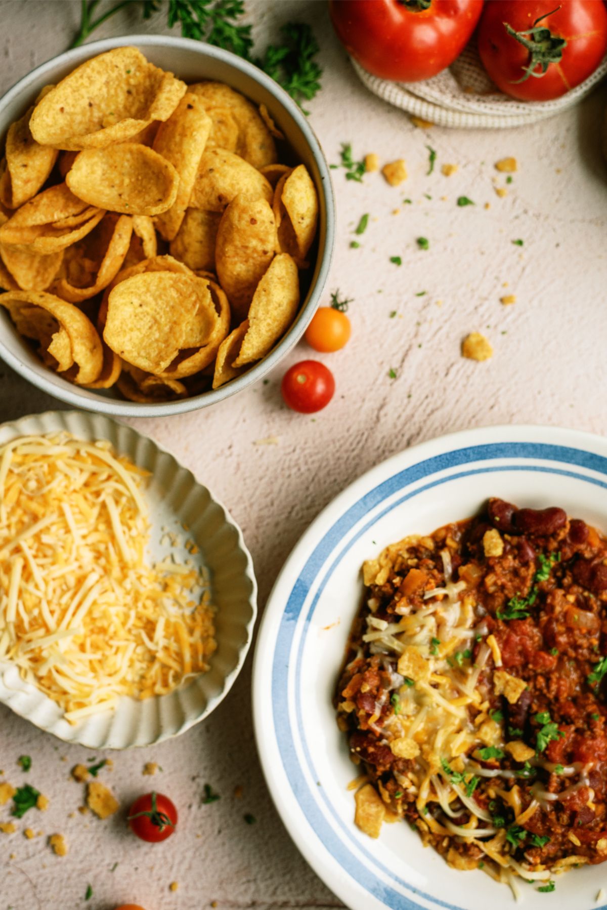 A bowl of Mom's Slow Cooker Chili with bowl of cheese and a bowl of chips