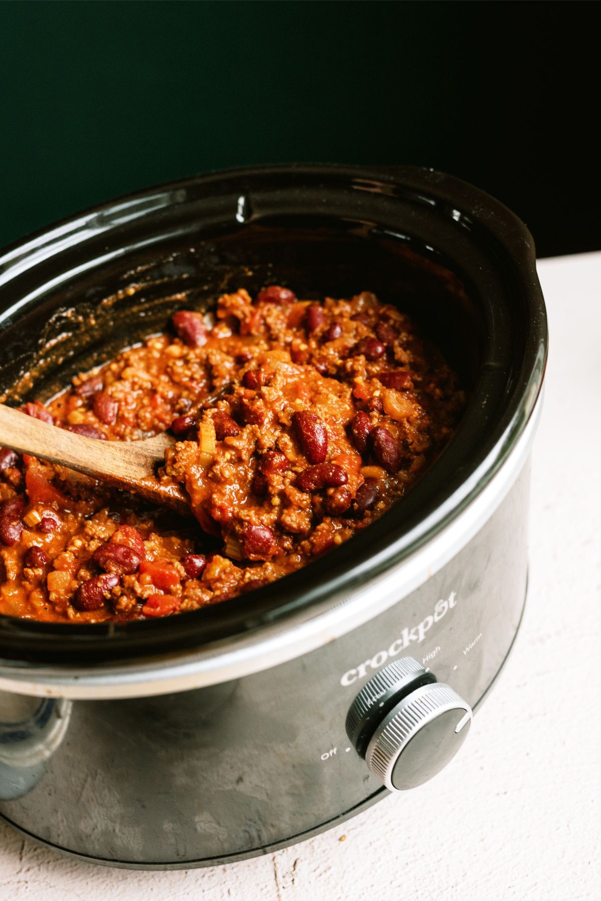 Mom's Slow Cooker Chili in the slow cooker with a wooden spoon