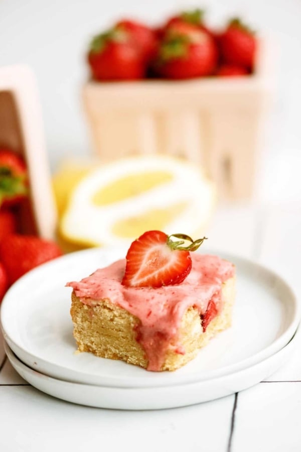 A strawberry lemon blondie on a plate with strawberries.