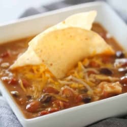 A bowl of Slow Cooker 8-Can Taco Soup with a tortilla chip in the center