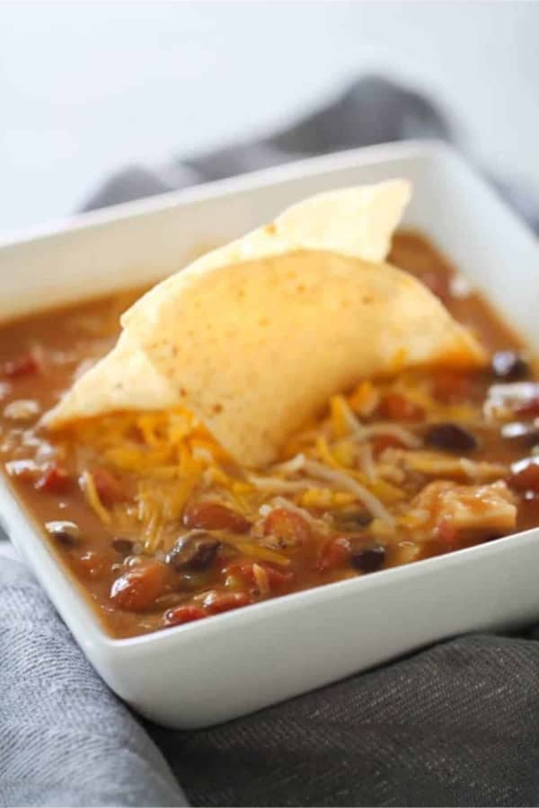 A bowl of Slow Cooker 8-Can Taco Soup with a tortilla chip in the center