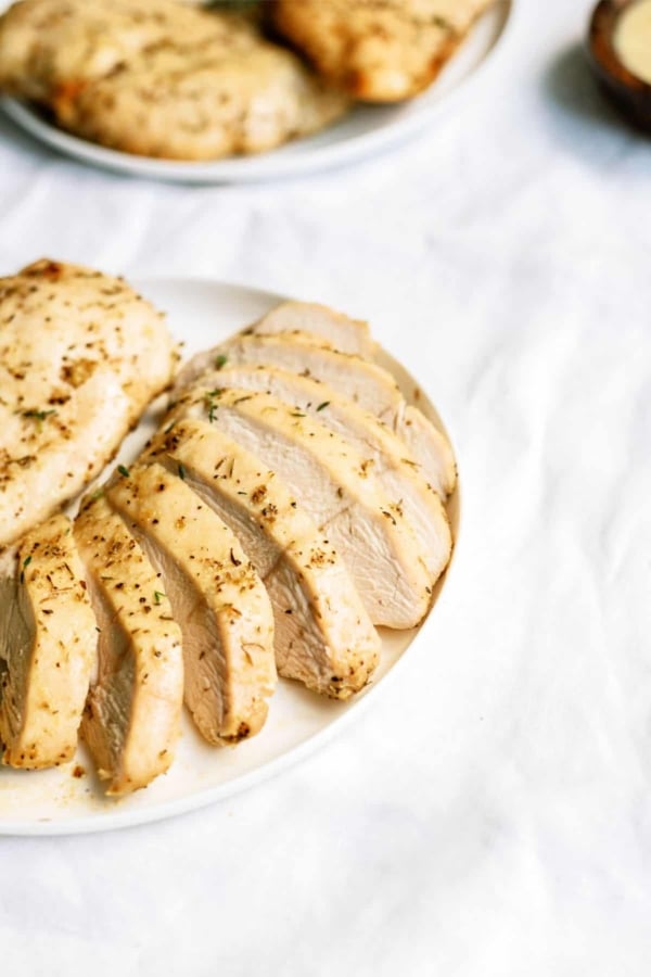 Baked Chicken Breast sliced on a plate with another baked chicken breast.