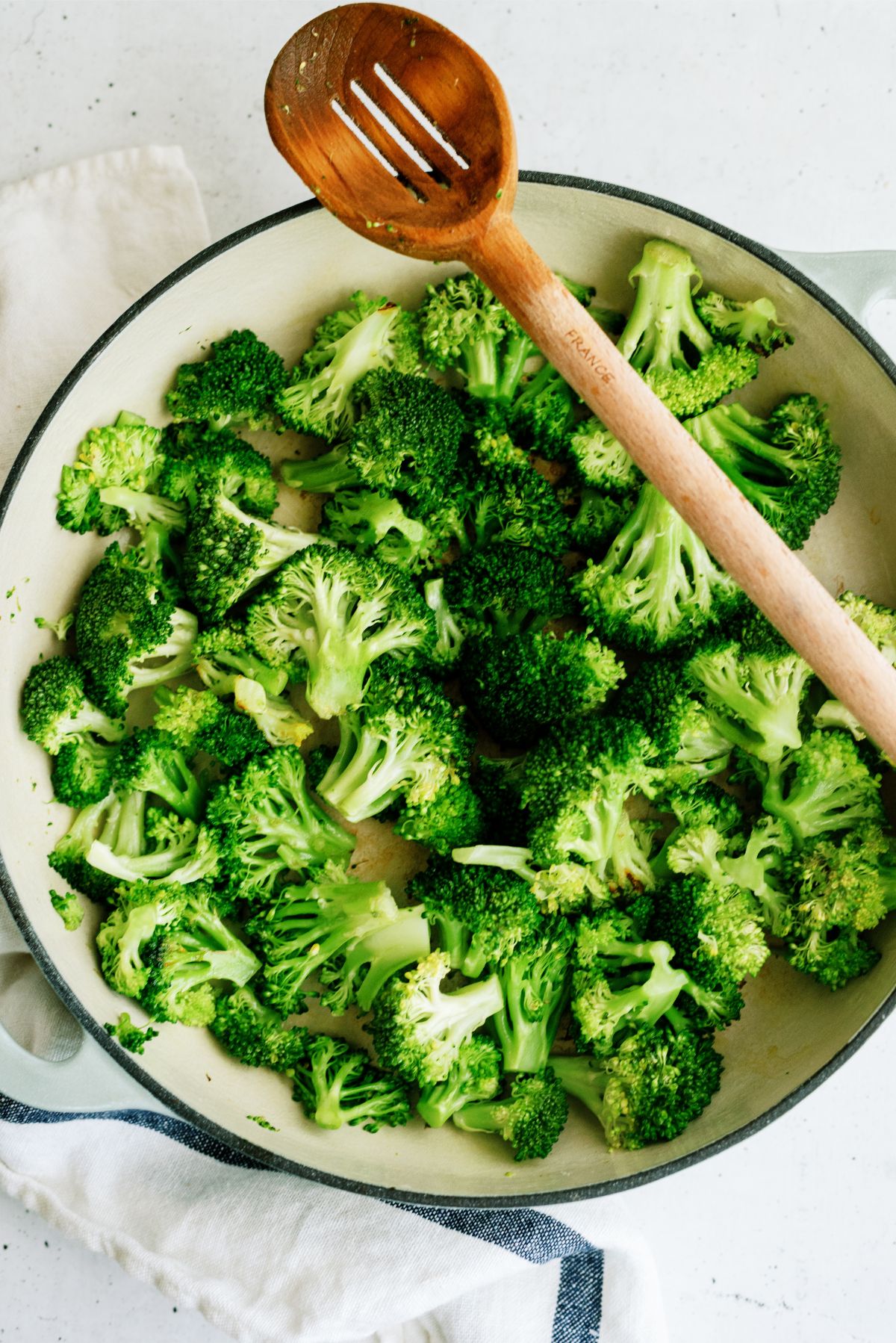 Sauteed broccoli in a pan with a wooden spoon