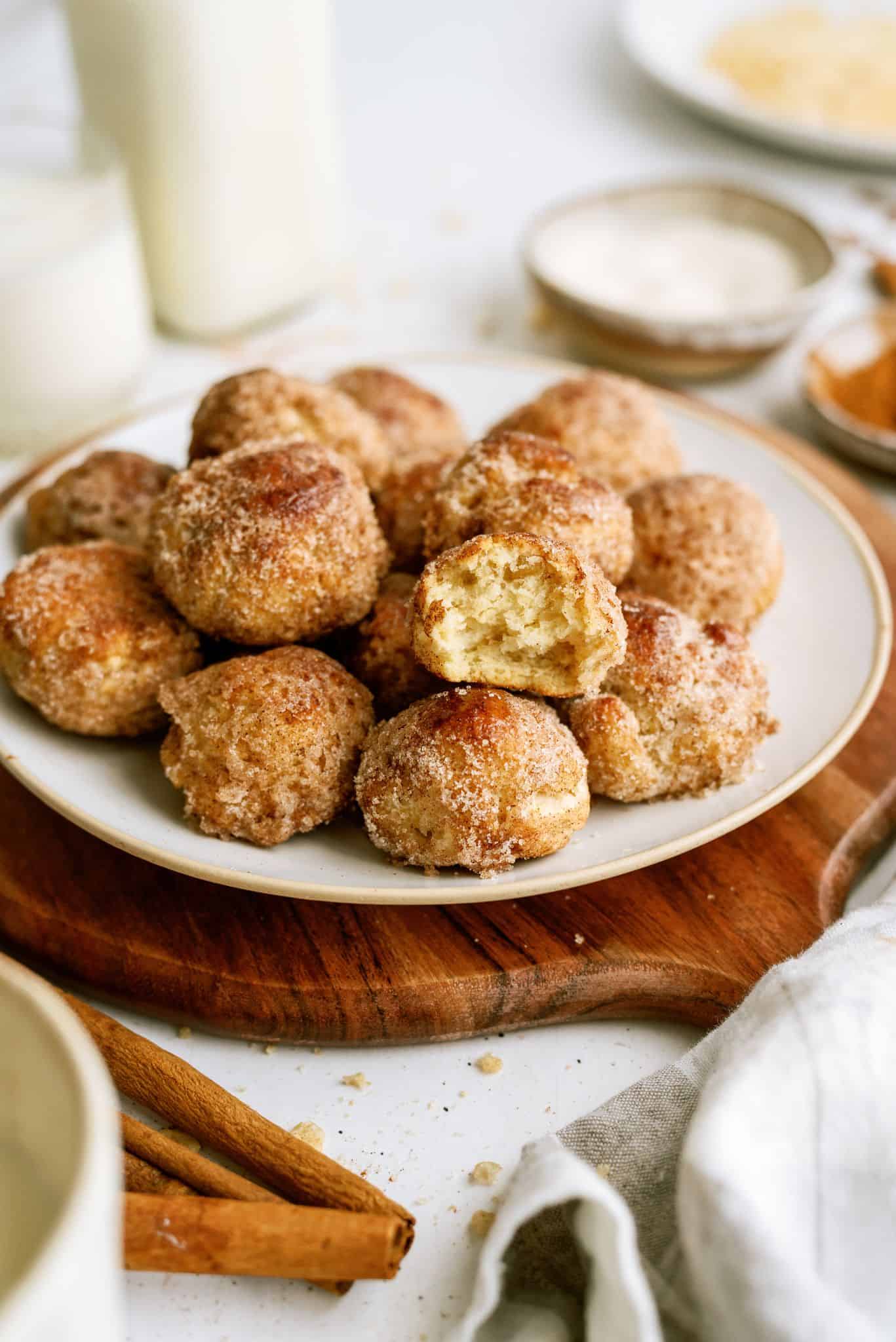 A plate stacked with Cinnamon Breakfast Bites with one cinnamon bite missing a bite.