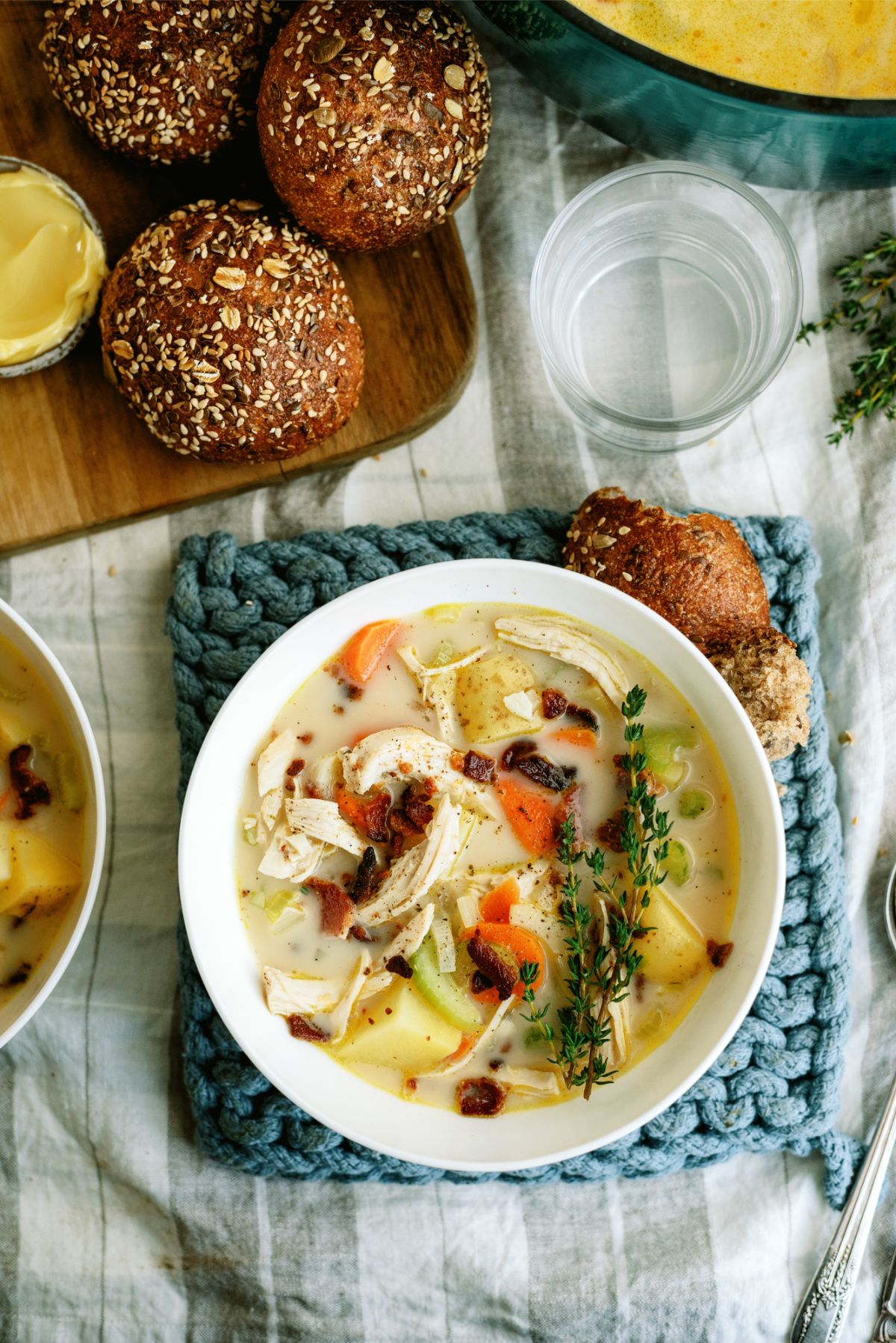 A bowl of Creamy Chicken and Potato Soup with rolls on the side
