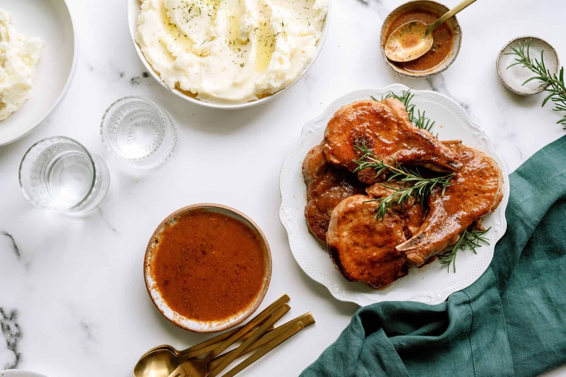 Instant Pot Cranberry Pork Chops on a serving plate with a side of BBQ sauce and mashed potatoes