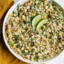 Mexican Street Corn Salad in a large white serving dish topped with two lime slices.