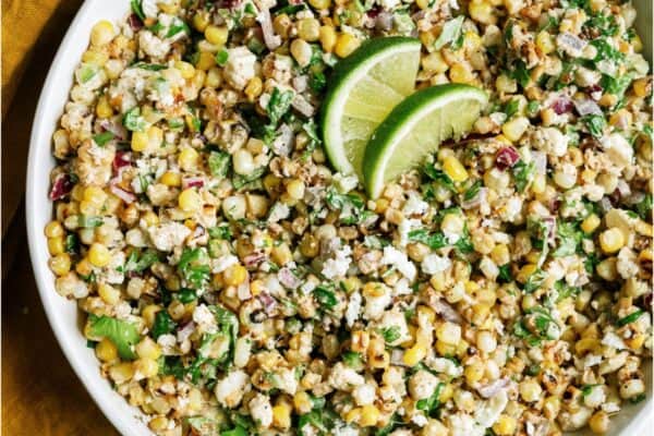 Mexican Street Corn Salad in a large white serving dish topped with two lime slices.
