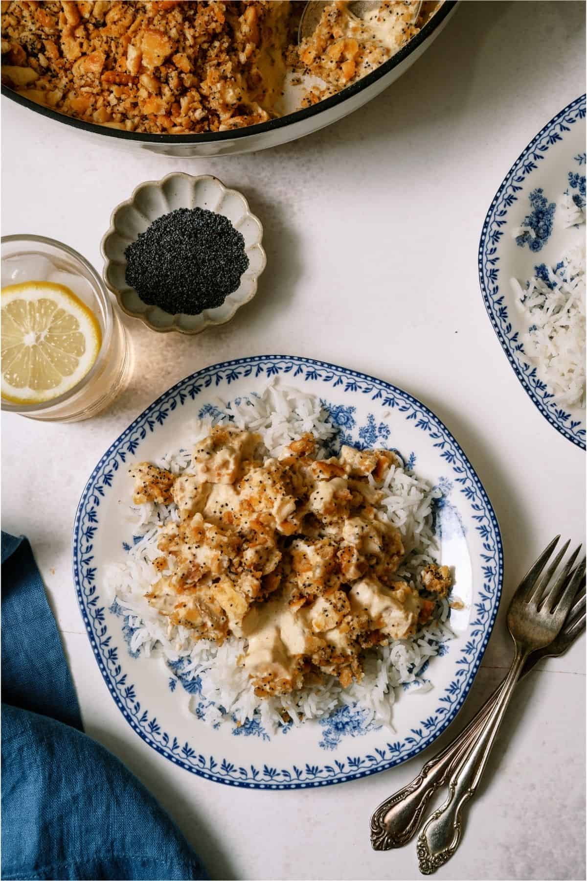A serving of Poppy Seed Chicken Casserole served over rice on a plate.