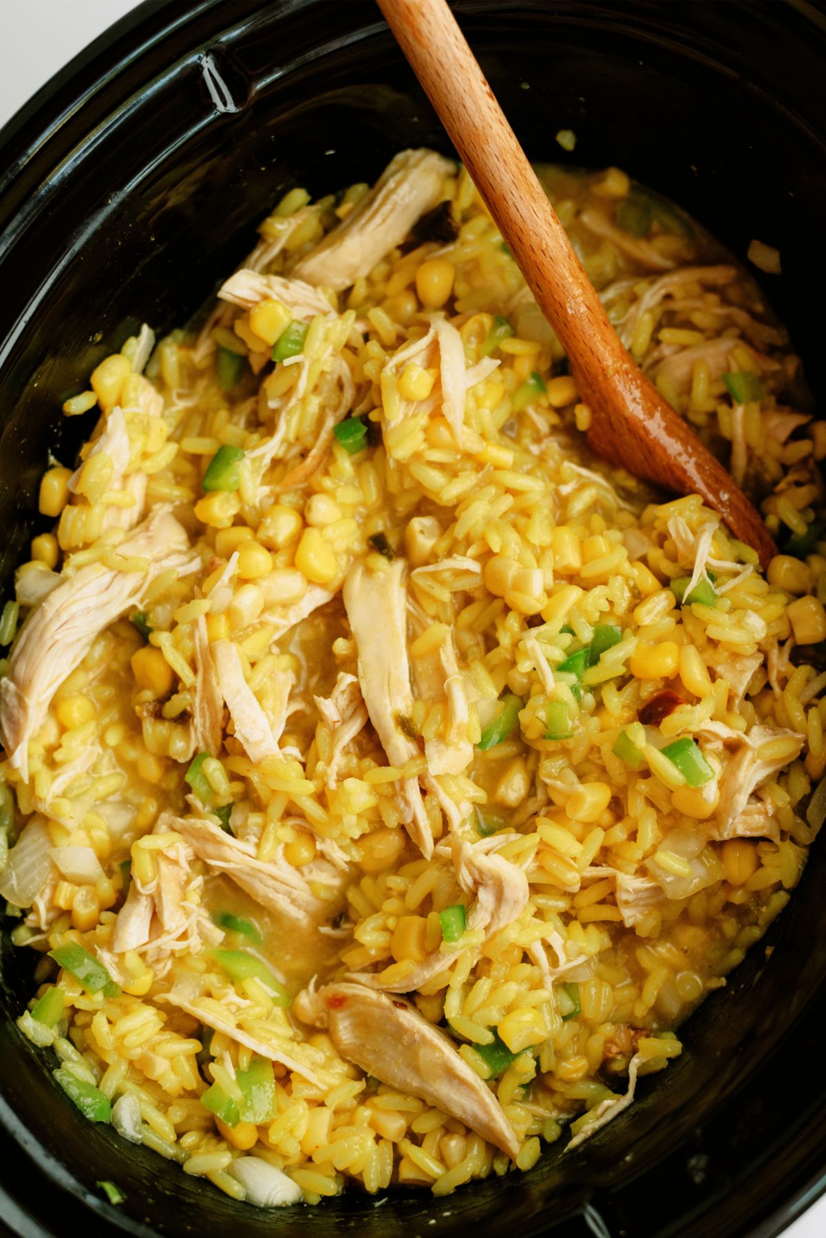 Slow Cooker Cheesy Chicken and Rice in slow cooker with wooden spoon