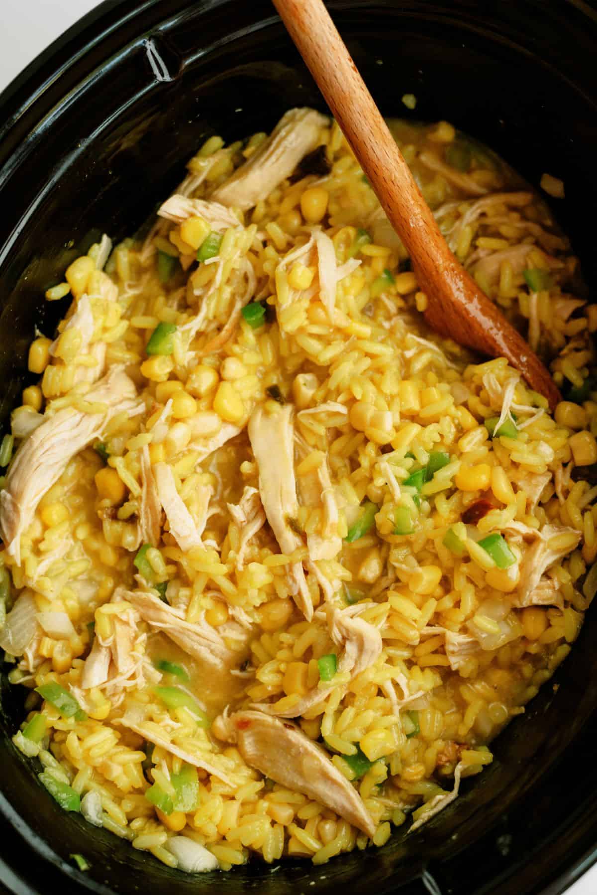 Slow Cooker Cheesy Chicken and Rice in slow cooker with wooden spoon