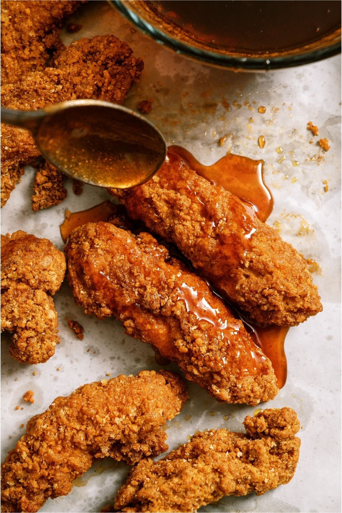 Spooning sticky sauce on top of baked chicken tender.