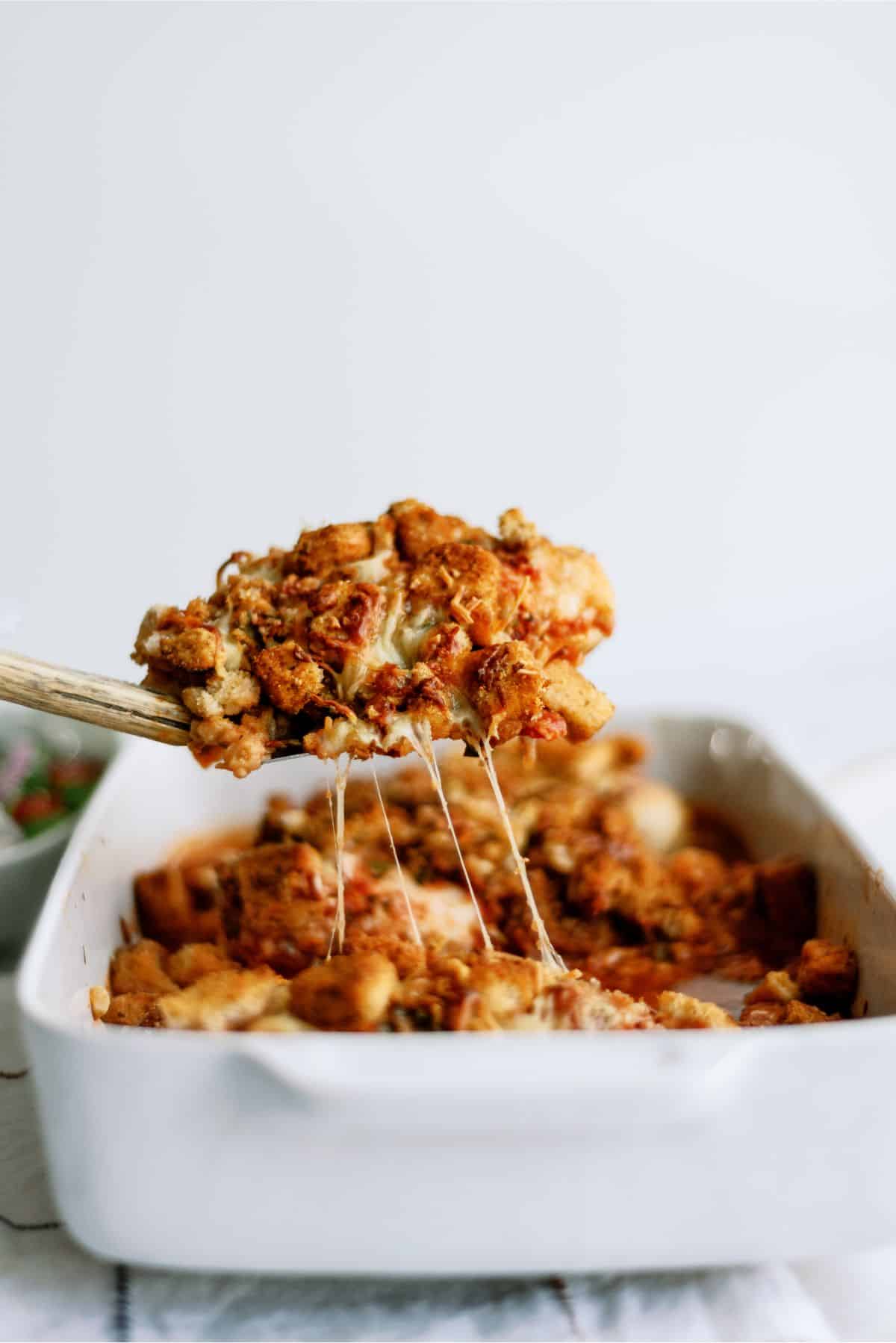 Baked Chicken Parmesan Casserole with a scoop being lifted out of the casserole dish