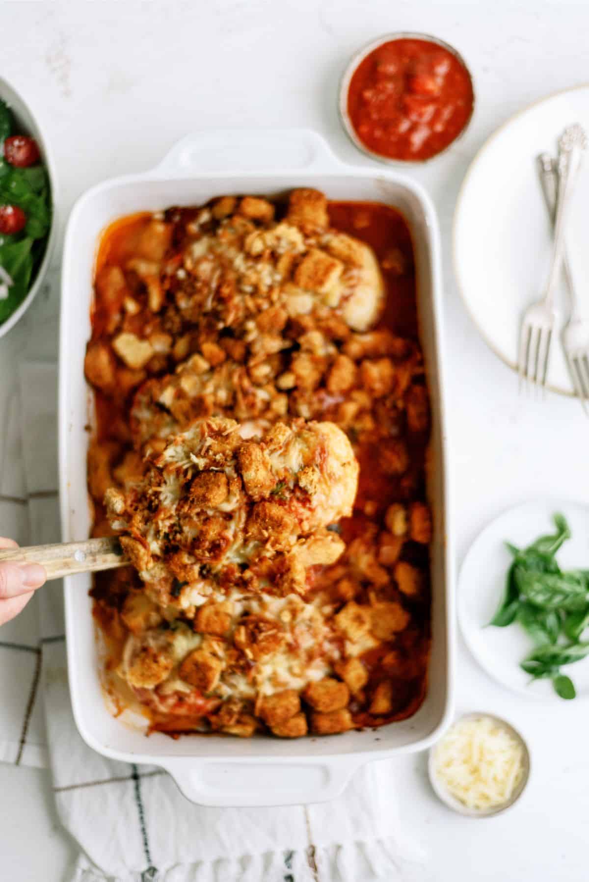 Baked Chicken Parmesan Casserole in a casserole dish with one scoop being lifted out